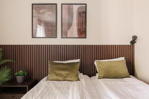 a bed with white sheets and green pillows at Calm Design Studio with Balcony & Parking in Pori