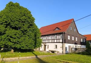 a large black and white barn with a tree at Ferienhof Saalendorf in Großschönau