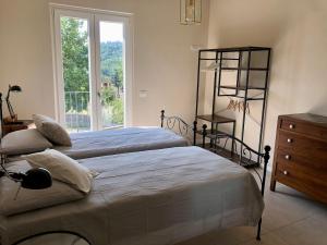 a bedroom with two beds and a dresser and a window at La Casina di Titty in Stia