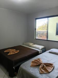 two beds in a room with a window at Hotel X in Valparaíso de Goiás