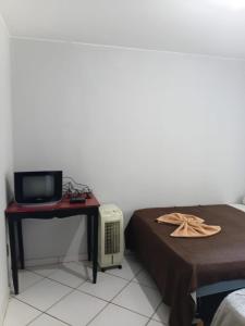 a bedroom with a bed and a desk and a tv at Hotel X in Valparaíso de Goiás
