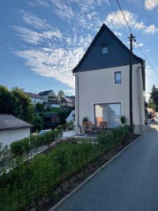 a white house with a black roof on a street at Elbsandsteinlodge in Sebnitz