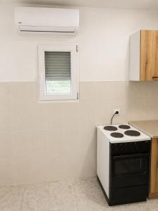 a white kitchen with a stove and a window at Apartman Suzana in Šušanj +6 photos