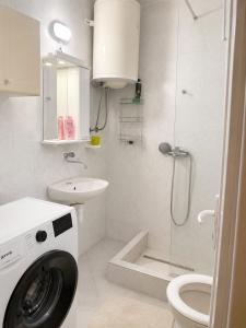 a white bathroom with a washing machine in it at Apartman Suzana in Šušanj