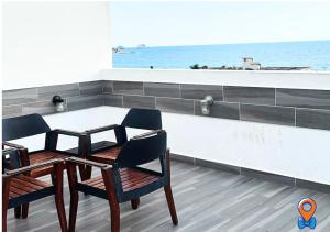 two chairs and a table in a room with the ocean at Depa Amplio Vista al Mar Cerca del Malecón in Mazatlán