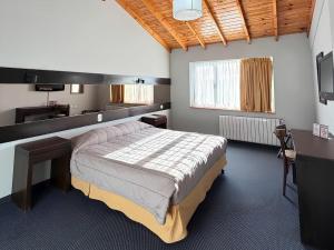 a bedroom with a bed and a desk and a television at Marcopolo Suites Calafate in El Calafate