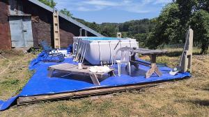 a boat sitting on a blue tarp with a table and chairs at Gite de Moulin Maurt in Xertigny