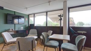 a waiting room with chairs and tables and windows at Campanile Epernay - Dizy 51530 in Épernay