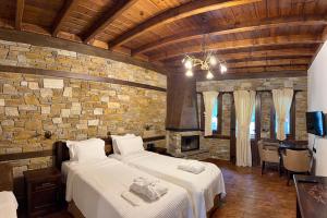 a bedroom with two beds and a stone wall at Thermes Pozar Resort in Kato Loutraki