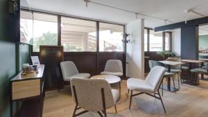 a waiting room with chairs and tables and windows at Campanile Epernay - Dizy 51530 in Épernay