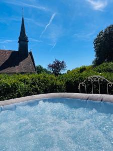 a hot tub with a chair and a church at Juste le bruit des fleurs in Saint-Nicolas-de-Sommaire