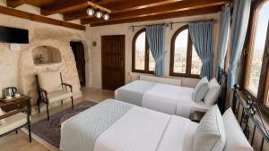 a bedroom with two beds and a chair and windows at Turquaz Cave Hotel in Göreme