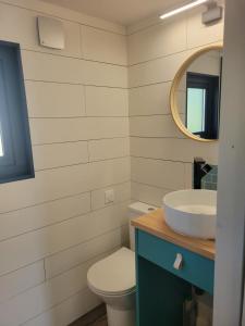 a bathroom with a sink and a toilet and a mirror at Camping LES ARBOUSIERS Carcans in Carcans