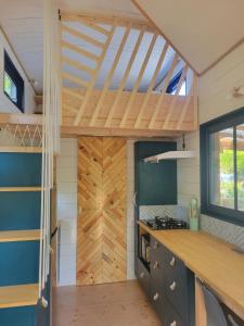 a kitchen in a tiny house with a wooden ceiling at Camping LES ARBOUSIERS Carcans in Carcans +23 photos