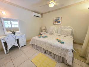 a bedroom with a bed and a table and a window at Mistle Cove 102 in Christ Church