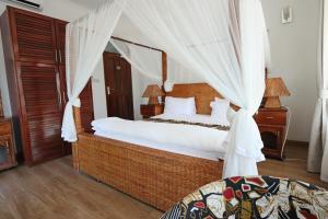 a bedroom with a large bed with a canopy at Villa Dahl Beach Resort in Dar es Salaam