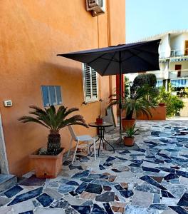a patio with a table and an umbrella at Cumpa Luca Bed and breakfast in Scalea