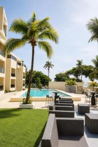 a pool with a palm tree and a table and chairs at Skylight Suites Hotel in San Felipe de Puerto Plata