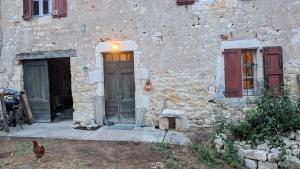 a stone building with a door and a chicken outside at Au soleil in Virac