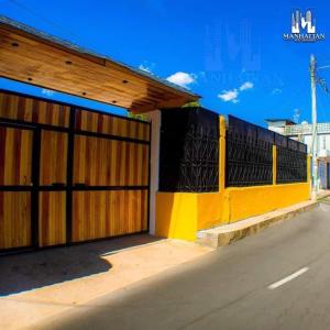 a building with a yellow and black fence next to a street at Hotel y Restaurante Manhattan in La Tenería