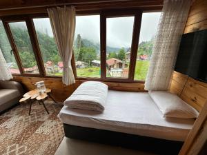 a bedroom with a bed and a large window at Ayder Serender Otel in Çamlıhemşin