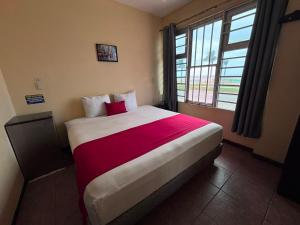 a bedroom with a large bed with a red blanket at Hotelito Fiesta Caribena in Coatzacoalcos