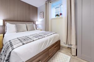 a bedroom with a large bed and a window at New & Modern Basement Suite - St Clair Hotel in Toronto