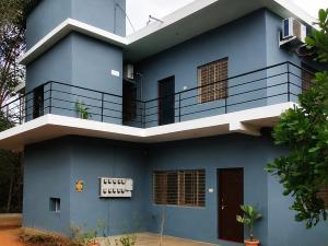 a blue house with a balcony on it at Nature Nest In in Auroville