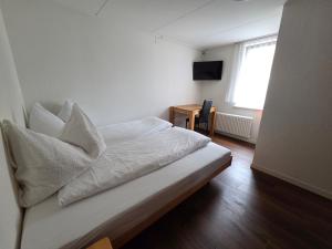 a bedroom with a bed with white sheets and a window at Hotel Frieden in Davos