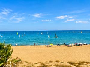 a group of people on a beach with sailboats in the water at Alcaraván, Isla Canela - By AC REAL in Isla Canela