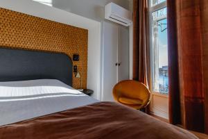 a bedroom with a bed and a chair and a window at Le Grand Hotel in Sète
