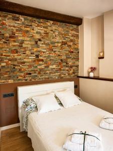 a bedroom with a white bed with a brick wall at Can Costals Cerezo in Pals
