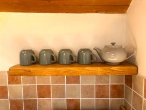 a shelf with cups and a tea pot on it at Abbey Place Net Loft in Mousehole