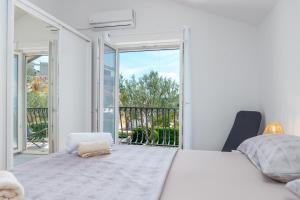 a white bedroom with a bed and a balcony at Guest house Bella in Slatine