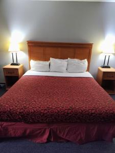a bed in a hotel room with two lamps on tables at Heritage Inn in Fairview +7 photos