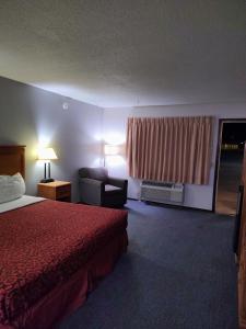 a hotel room with a bed and a chair and a window at Heritage Inn in Fairview