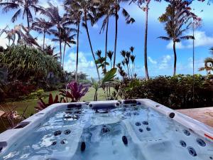 a bath tub with palm trees in the background at Utopia Beach Front Estate in Kilauea