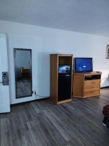 a room with a tv and a dresser and a mirror at Heritage Inn in Fairview