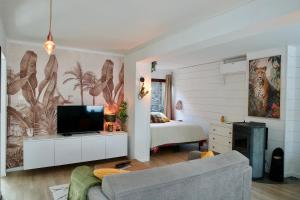 a bedroom with a bed and a tv and a couch at Escapade tropicale au Costa Rica in Profondeville