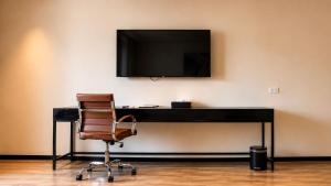 a desk with a chair and a television on a wall at Grand Resort & Residences in Belize City
