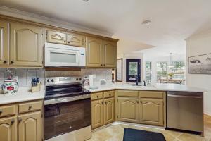a kitchen with wooden cabinets and a microwave at <1 Block to Trails! Conway Biker & Hikers Haven in Conway