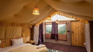 a bedroom with a bed and a large window at Mystique Meadows Swiss Cottages in Nubra