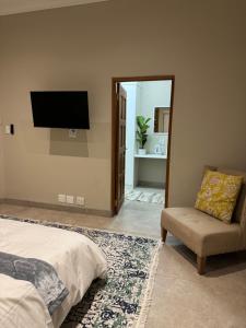 a bedroom with a bed and a chair and a mirror at Villa Euris Guesthouse in Brits