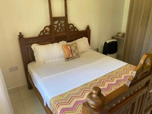 a bed with a wooden frame and pillows on it at Nyumba Nzuri in Ukunda, Diani in Ukunda