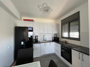 a kitchen with white cabinets and a black refrigerator at סוויטת נוף התכלת in Migdal
