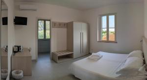 a white bedroom with a large bed and a bathroom at Agrialbergo Capalbio La Sugherella - Hotel Il Cipresso in Capalbio