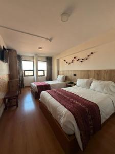 a hotel room with two beds and a tv at Hotel Prisma Cusco in Cusco