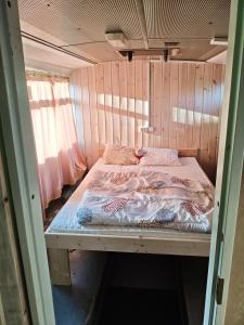 a bed in a room with a wooden wall at Glampingbus in Kärdla