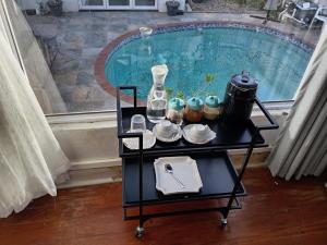a table with dishes and a bottle on it next to a pool at M Group B&B in King Williamʼs Town