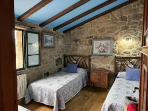 two beds in a room with stone walls at BLEU MAISON-PAZO 1 CL in Campo Lameiro
